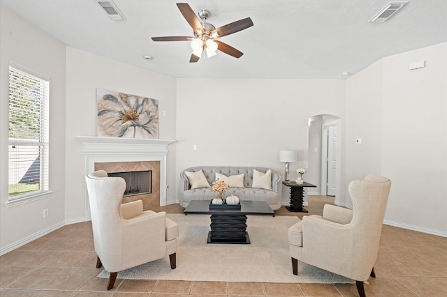 living room featuring a tile fireplace, ceiling fan, and light tile patterned flooring