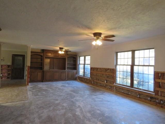 unfurnished living room featuring a wealth of natural light, ceiling fan, and a textured ceiling