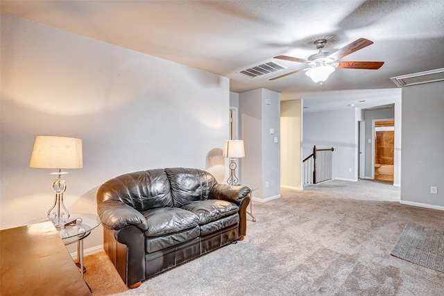 living room featuring light carpet, ceiling fan, and a textured ceiling