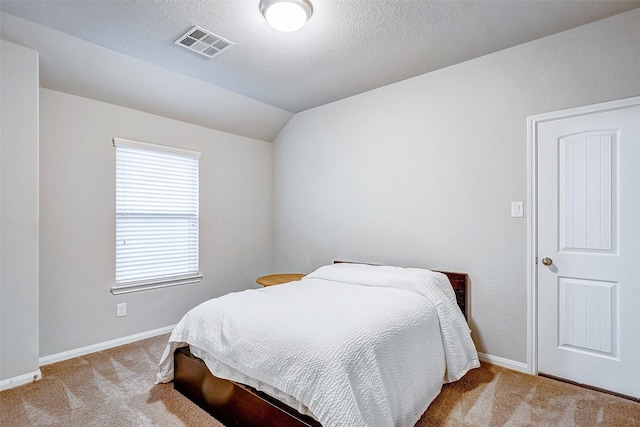 bedroom featuring a textured ceiling, light colored carpet, and lofted ceiling