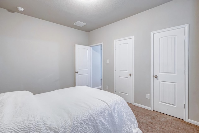 bedroom with a textured ceiling and light colored carpet