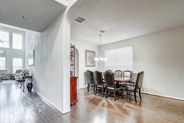 dining area with wood-type flooring and a notable chandelier