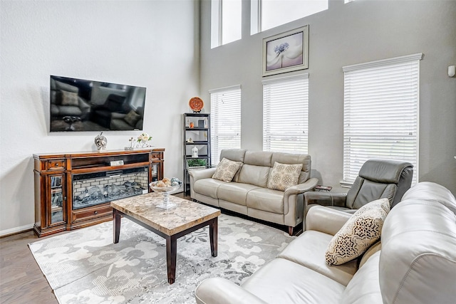 living room with light hardwood / wood-style flooring and a towering ceiling