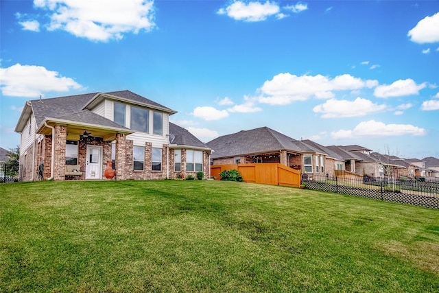 back of property with a yard and ceiling fan