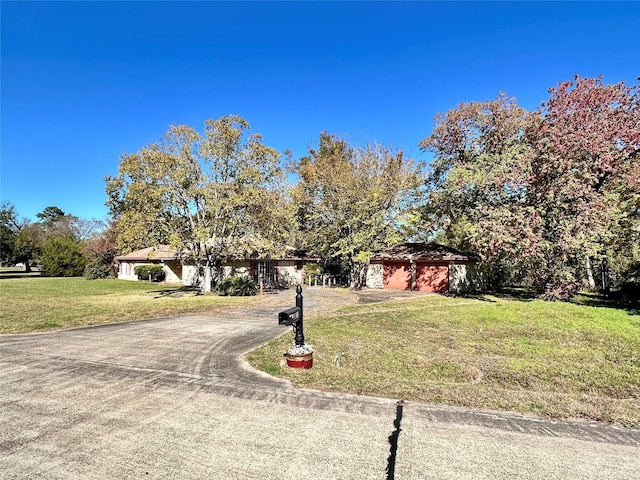 view of property hidden behind natural elements featuring a garage and a front lawn