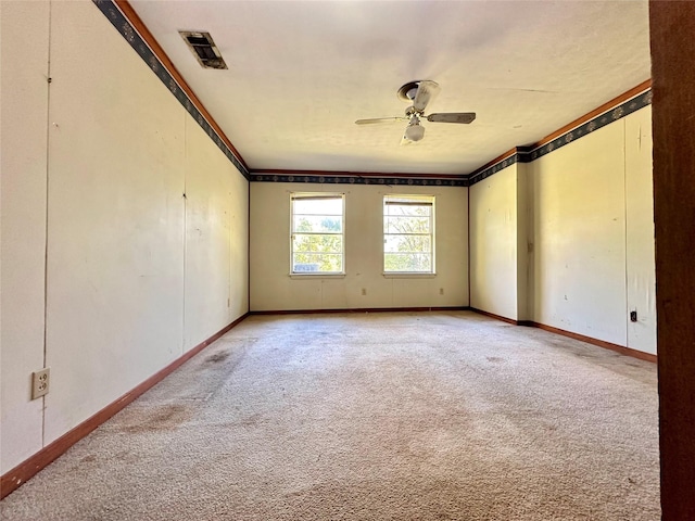 carpeted spare room featuring ceiling fan and crown molding