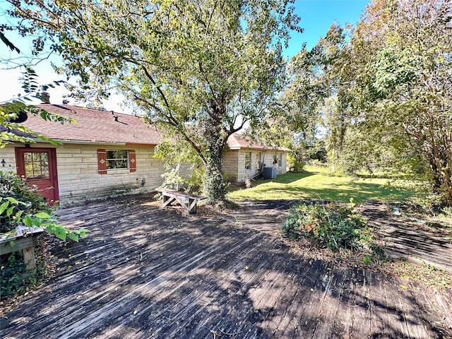 exterior space with a lawn, cooling unit, and a deck