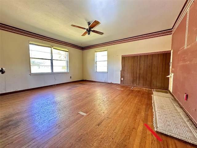 empty room featuring ceiling fan, wood-type flooring, and crown molding