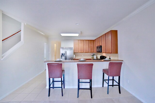 kitchen featuring a breakfast bar area, backsplash, black appliances, and ornamental molding