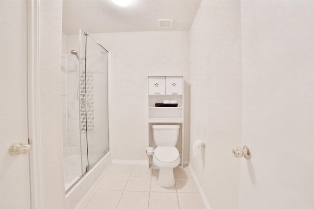 bathroom featuring tile patterned floors, a shower with door, and toilet