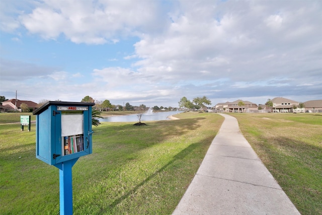 view of home's community featuring a lawn and a water view