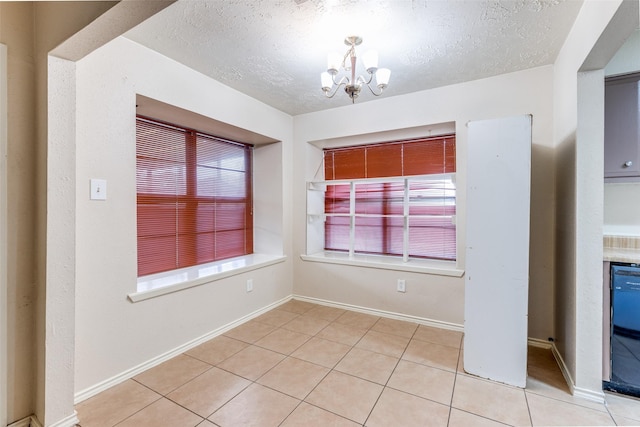 unfurnished dining area featuring a chandelier, light tile patterned floors, and a textured ceiling