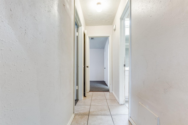 corridor with light tile patterned floors and a textured ceiling