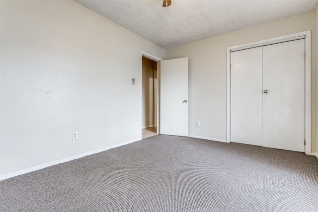 unfurnished bedroom with ceiling fan, a closet, carpet, and a textured ceiling