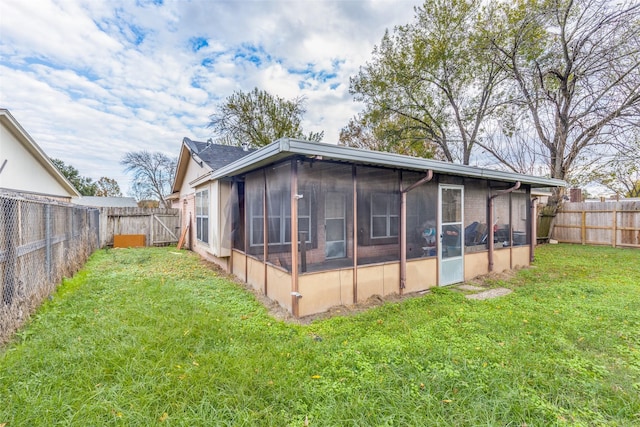 rear view of house with a lawn and a sunroom