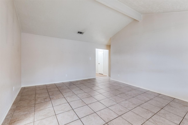 spare room with light tile patterned floors, lofted ceiling with beams, and a textured ceiling