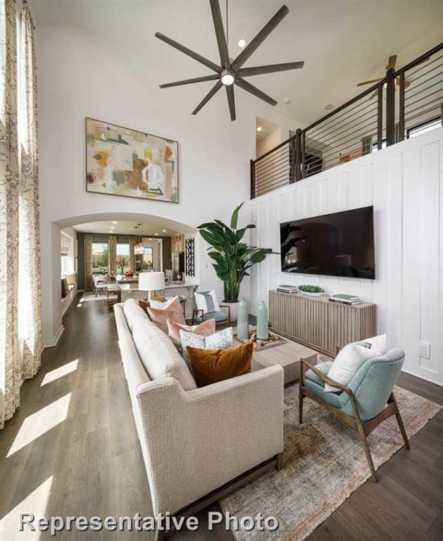 living room with dark hardwood / wood-style floors, ceiling fan, and a towering ceiling