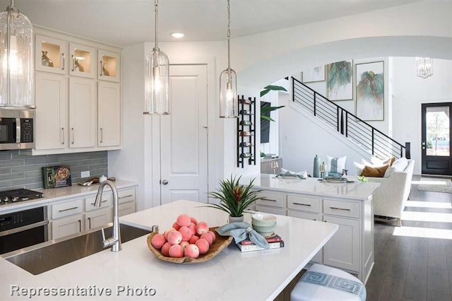 kitchen featuring white cabinetry, sink, a center island, backsplash, and appliances with stainless steel finishes