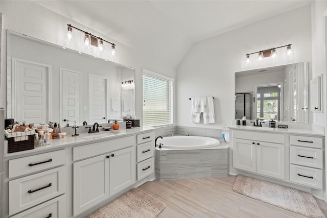 bathroom with vanity, independent shower and bath, a wealth of natural light, and vaulted ceiling