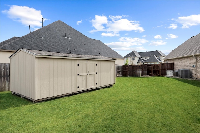 rear view of house featuring a lawn, central air condition unit, and a storage unit