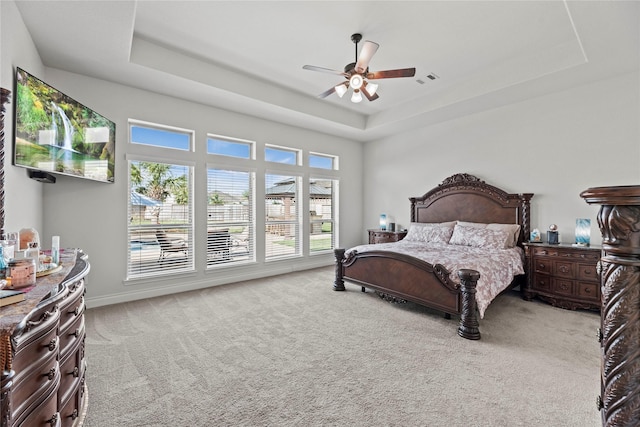 carpeted bedroom featuring a tray ceiling and ceiling fan