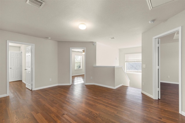 empty room featuring a textured ceiling, dark hardwood / wood-style flooring, and ceiling fan