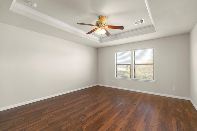 empty room featuring a tray ceiling, ceiling fan, and dark wood-type flooring