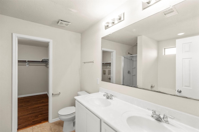 bathroom featuring vanity, tile patterned floors, toilet, walk in shower, and a textured ceiling