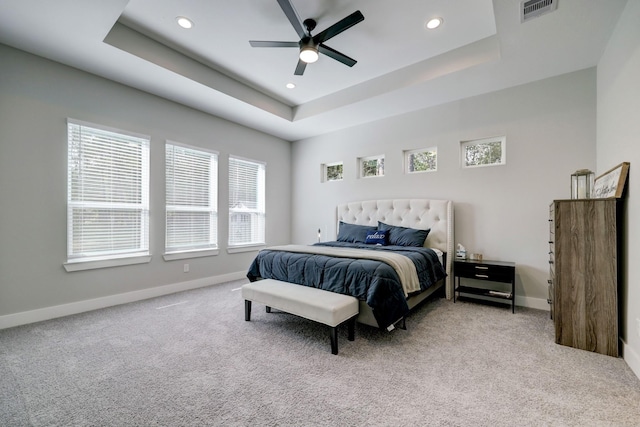 carpeted bedroom featuring a raised ceiling and ceiling fan