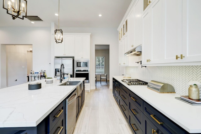 kitchen featuring decorative backsplash, stainless steel appliances, sink, pendant lighting, and white cabinets