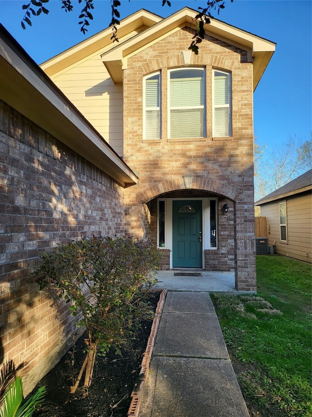 view of exterior entry featuring a yard and central AC unit