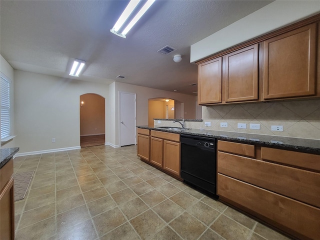 kitchen with backsplash, dark stone countertops, dishwasher, and sink