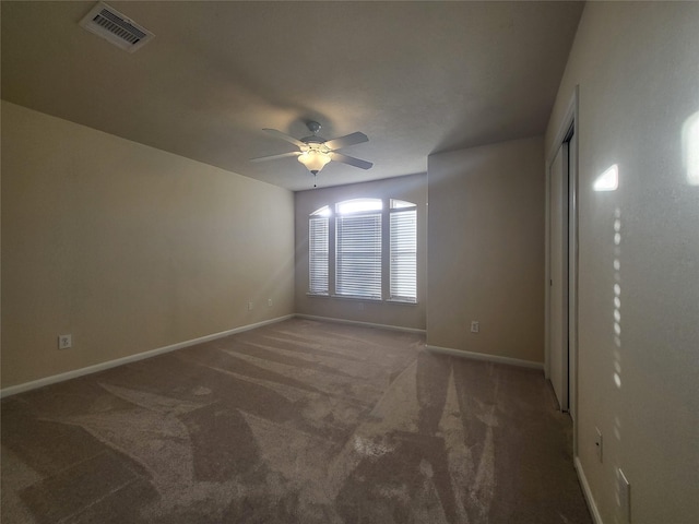 empty room with ceiling fan and dark colored carpet