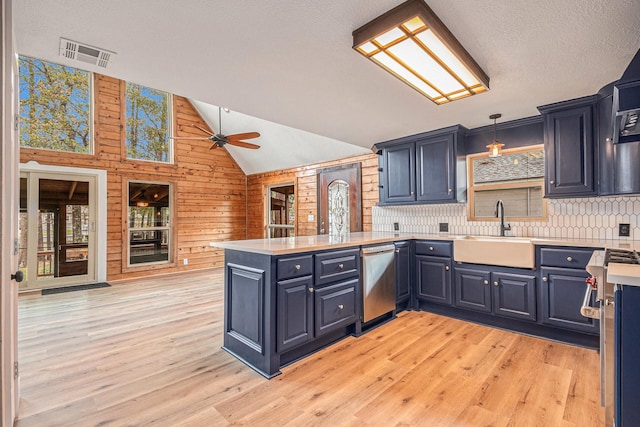 kitchen with kitchen peninsula, sink, pendant lighting, dishwasher, and lofted ceiling