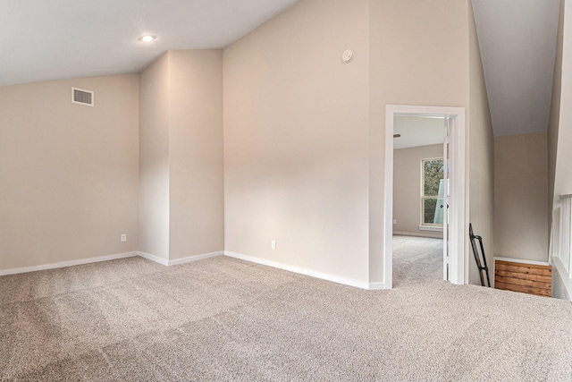 carpeted spare room with vaulted ceiling