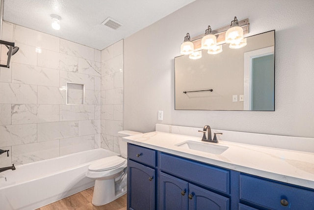 full bathroom featuring a textured ceiling, toilet, hardwood / wood-style flooring, vanity, and tiled shower / bath