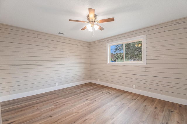 unfurnished room with wooden walls and light hardwood / wood-style flooring