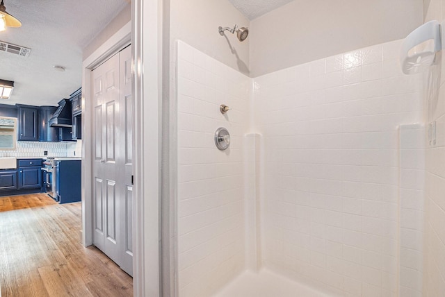 bathroom featuring sink, backsplash, a shower, wood-type flooring, and a textured ceiling