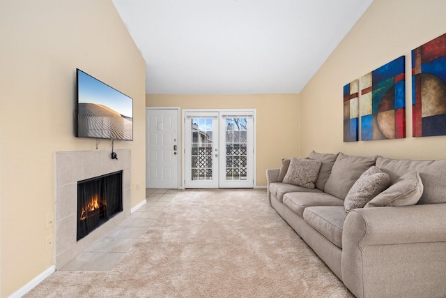 living room with light colored carpet, vaulted ceiling, and a tiled fireplace