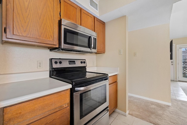 kitchen featuring stainless steel appliances and light colored carpet