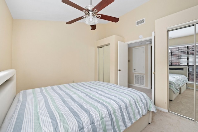 carpeted bedroom featuring ceiling fan and two closets