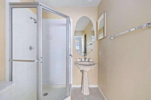 bathroom featuring tile patterned flooring, toilet, and an enclosed shower