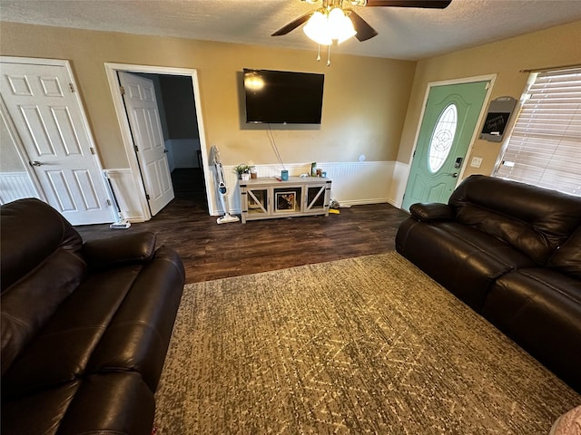 living room with ceiling fan, dark hardwood / wood-style floors, and a textured ceiling