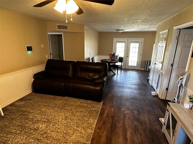 living room with french doors, a textured ceiling, ceiling fan, and dark wood-type flooring