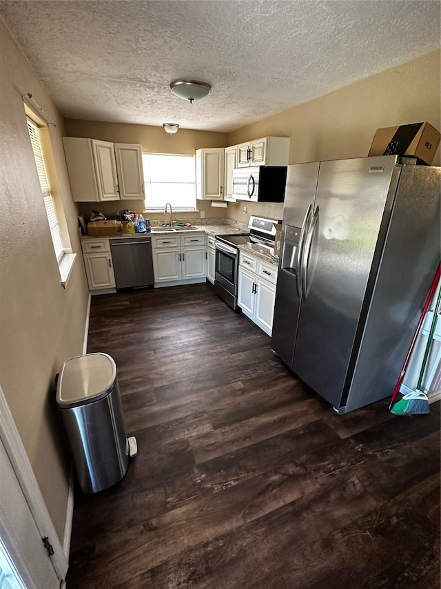 kitchen with white cabinets, sink, dark hardwood / wood-style floors, a textured ceiling, and stainless steel appliances