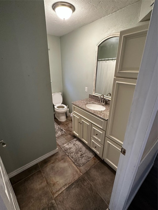 bathroom with vanity, toilet, and a textured ceiling