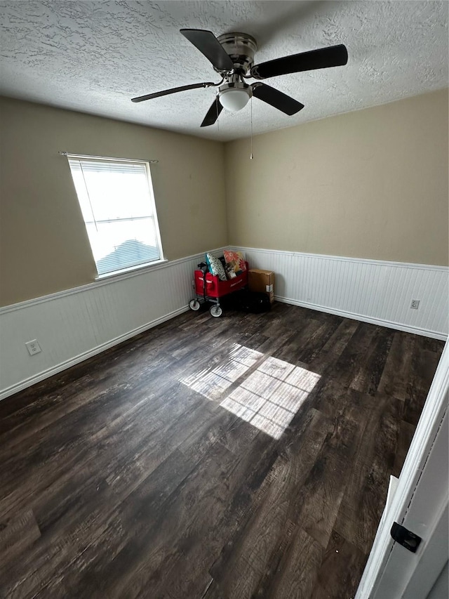 unfurnished room with a textured ceiling, ceiling fan, and dark wood-type flooring