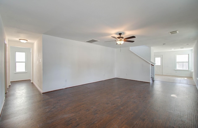 unfurnished room featuring a healthy amount of sunlight, ceiling fan, and dark wood-type flooring