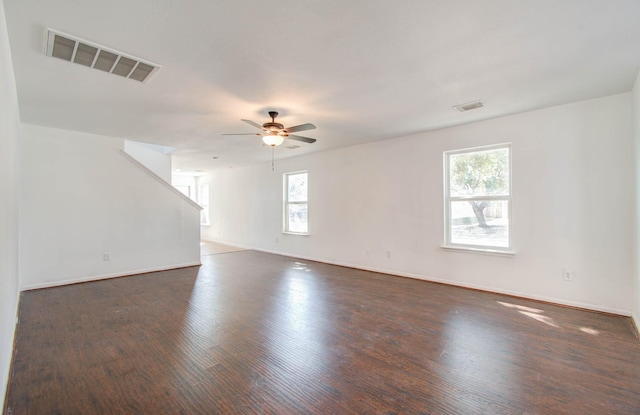 empty room with plenty of natural light, ceiling fan, and dark hardwood / wood-style flooring