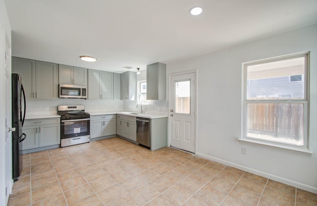 kitchen with tasteful backsplash, sink, light tile patterned floors, and stainless steel appliances